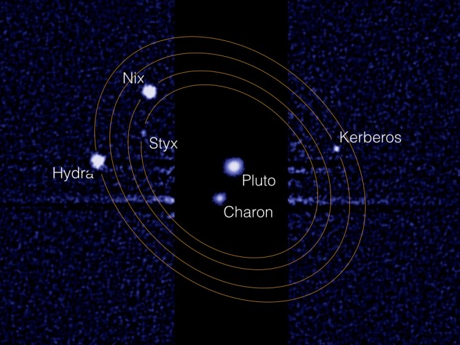 Questa immagine composita ottenuta dallo Hubble Space Telescope mostra Plutone e la sua luna maggiore Caronte al centro. A destra e sinistra si possono scorgere le quattro lune minori che orbitano questa sorta di “pianeta binario”. Essendo estremamente meno luminose, le quattro lune hanno richiesto un tempo di esposizione 1000 volte superiore rispetto alla coppia centrale. Crediti: NASA, ESA, Mark Showalter (SETI Institute)