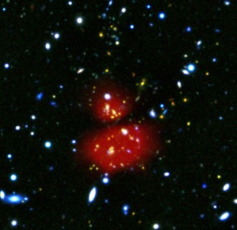 Immagine composita che evidenzia l'emissione nell'infrarosso della regione centrale dell'ammasso di galassie XDPCJ0044 realizzata grazie alle osservazioni dello strumento PACS del satellite Herschel. Crediti: ESA/Herschel/J. Santos et al. 2015; NAOJ/Subaru; ESA/VLT/Hawk-I