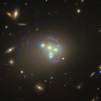 L'immagine  dell'Hubble Space Telescope mostra il ricco ammasso di galassie Abell 3827. Le strane strutture celesti che circondano le galassie centrali sono la vista di una galassia molto più lontana prodotta dall'effetto della lente gravitazionale. La distribuzione della materia oscura nell'ammasso è mostrata con linee di colore blu. Vi è un'estremità di materia oscura per la galassia a sinistra significativamente spostato dalla posizione della galassia stessa, che potrebbe essere prodotto dalla prolungata interazione tra materia oscura.