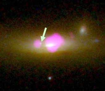 Immagine della galassia SDSS J1126+2944 ripresa in ottico da Hubble Space Telescope e (in viola) in raggi X da Chandra, che rivelano l’ubicazione dei due buchi neri messi assieme dal processo di merging di due galassie più piccole. La freccia indica il buco nero “spoglio” di stelle associate. Crediti: University of Colorado Boulder.