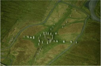 Veduta aerea di Callanish. Il cerchio di pietre ha un diametro di 13 metri, e mostra un lungo viale in direzione nord-sud (il sud è dove si trova il cerchio). La conformazione a croce permette di individuare anche gli altri punti cardinali. Crediti: RCAHMS (Aerial Photography Collection)