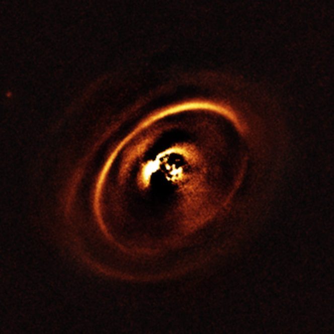 La zona centrale dell'immagine appare scura perchè SPHERE blocca la luce della stella centrale per rivelare le strutture molto più deboli che la circondano. Crediti: ESO, J. de Boer et al.