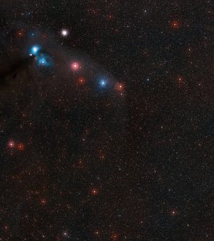 Questa panoramica mostra il cielo intorno alla debole stella di neutroni RX J1856.5-3754 nella costellazione meridionale della Corona Australe. In questa zona di cielo si vedono molte nebulose scure e brillanti che circondano la stella variabile R Coronae Australis (in alto a sinistra) e l'ammasso globulare NGC 6723. La stella di neutroni è troppo debole per essere vista in questa fotografia, ma si trova praticamente al centro dell'immagine. Crediti: ESO/Digitized Sky Survey 2, Davide De Martin